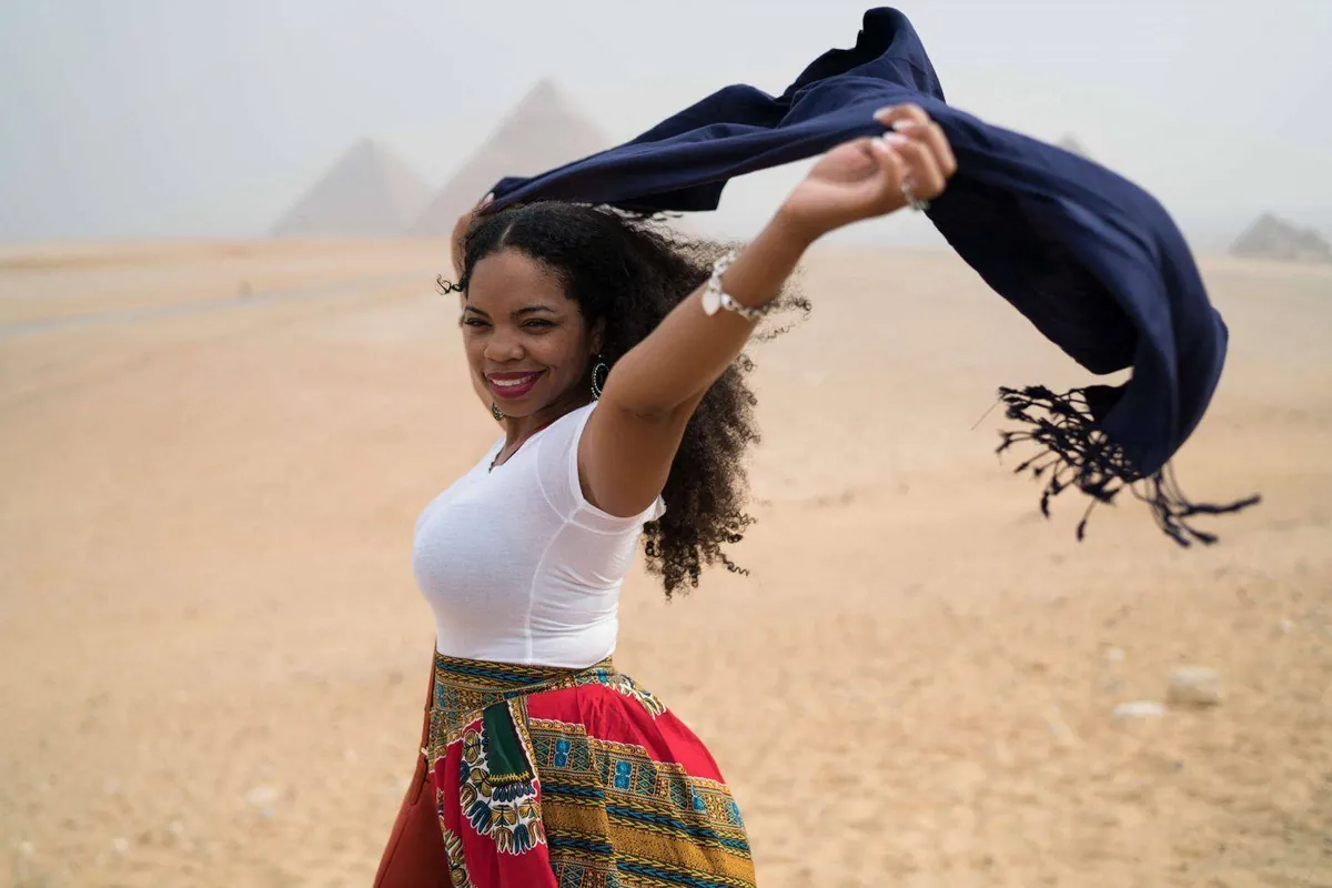 Claire B. Soares in front of the pyramids of Giza, a scarf flying in the wind